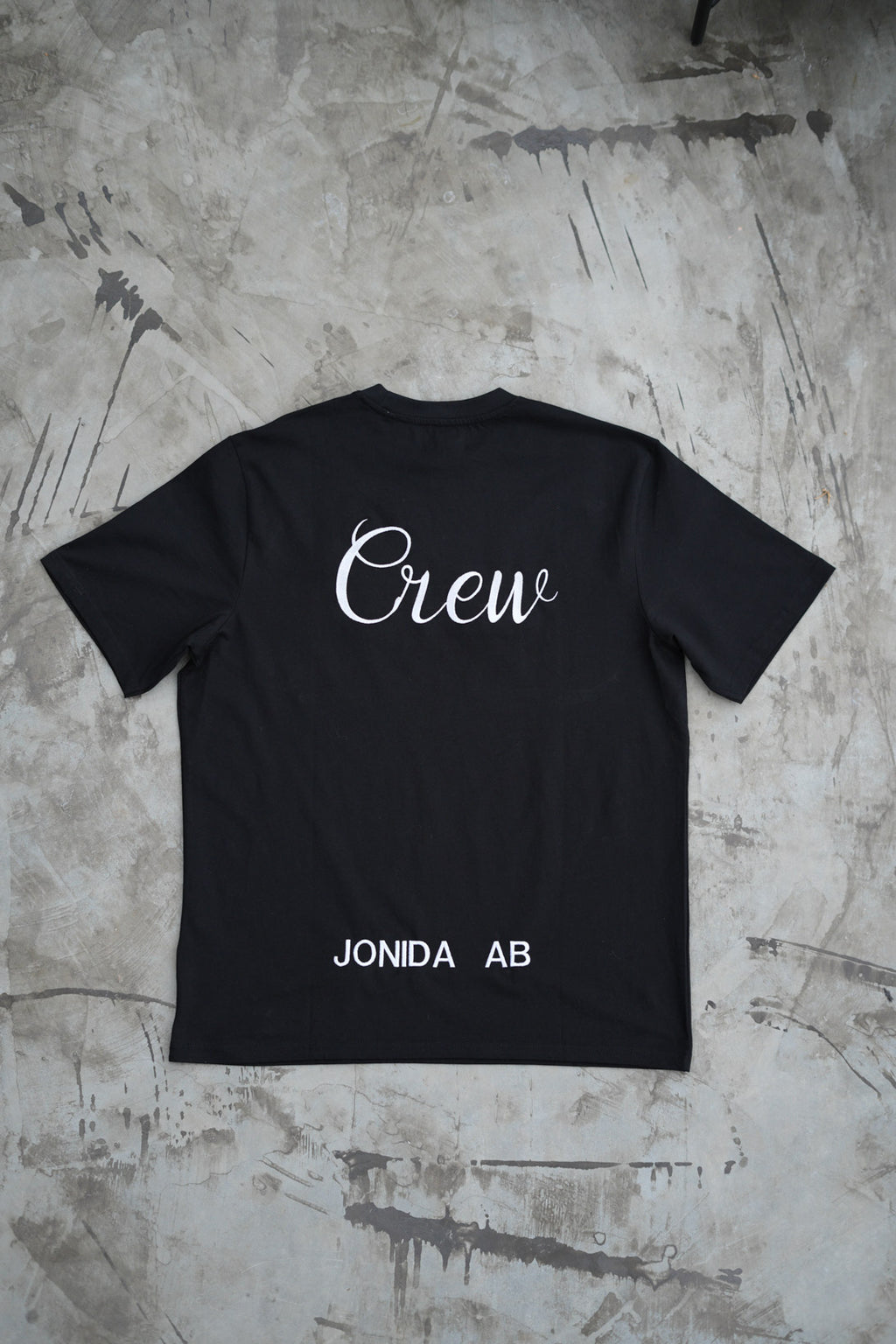 Svart t-shirt med företags logga broderad på ryggen. 
