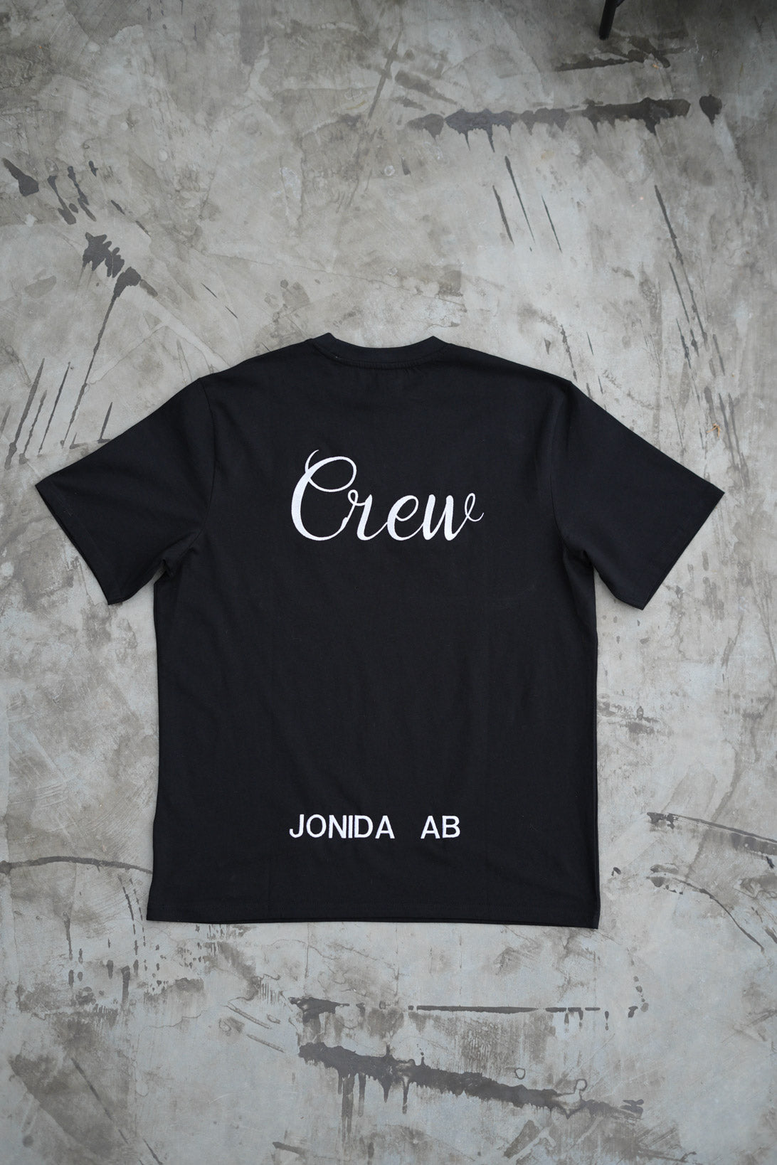 Svart t-shirt med företags logga broderad på ryggen. 