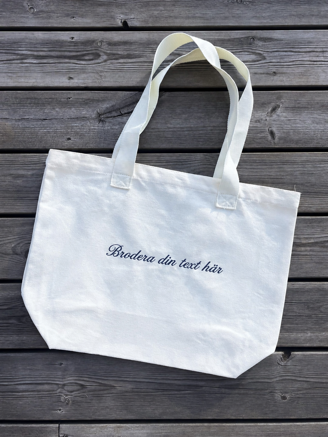 Totebag med broderad text på terassen. 