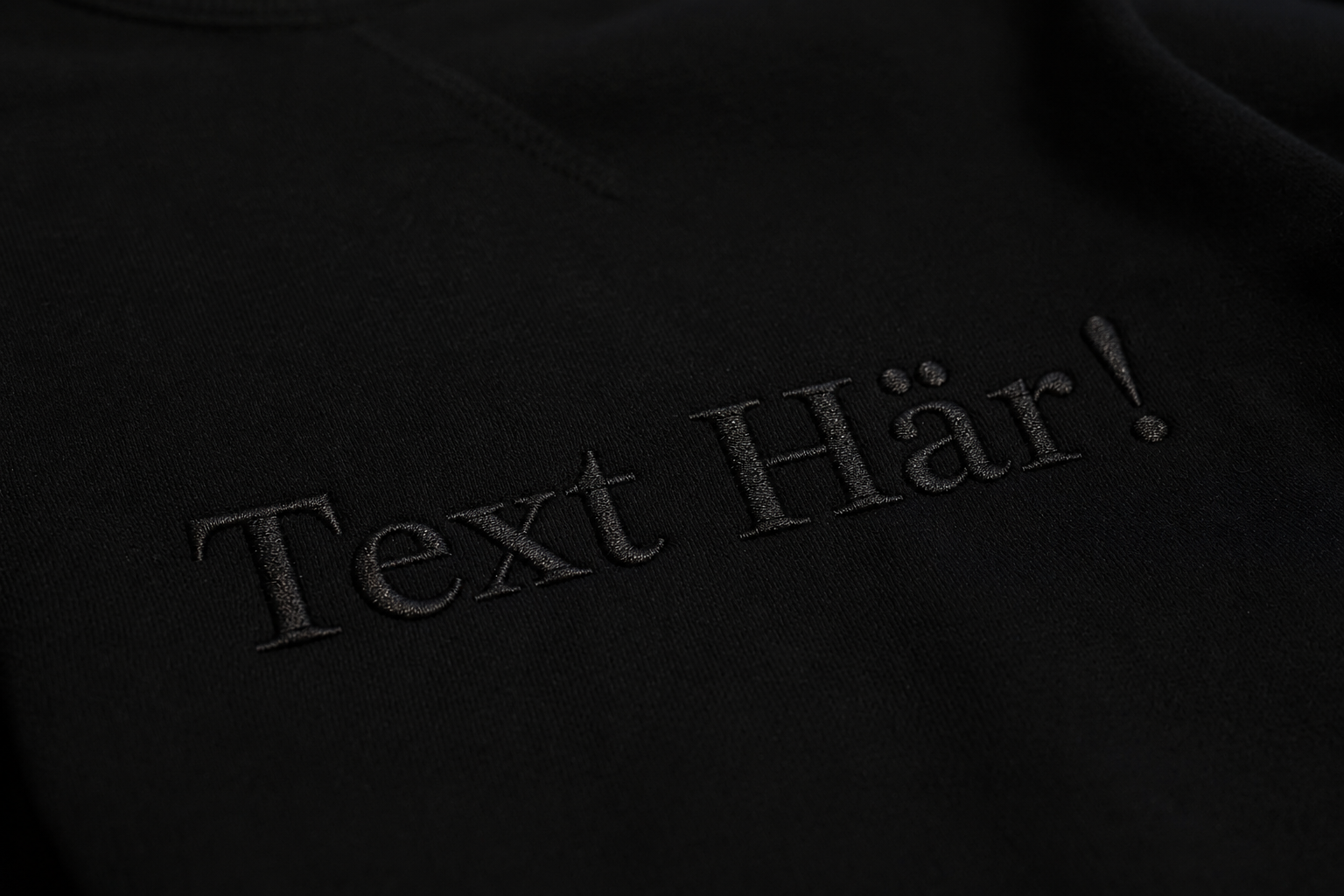 Svart broderad text på svart hoodie. 