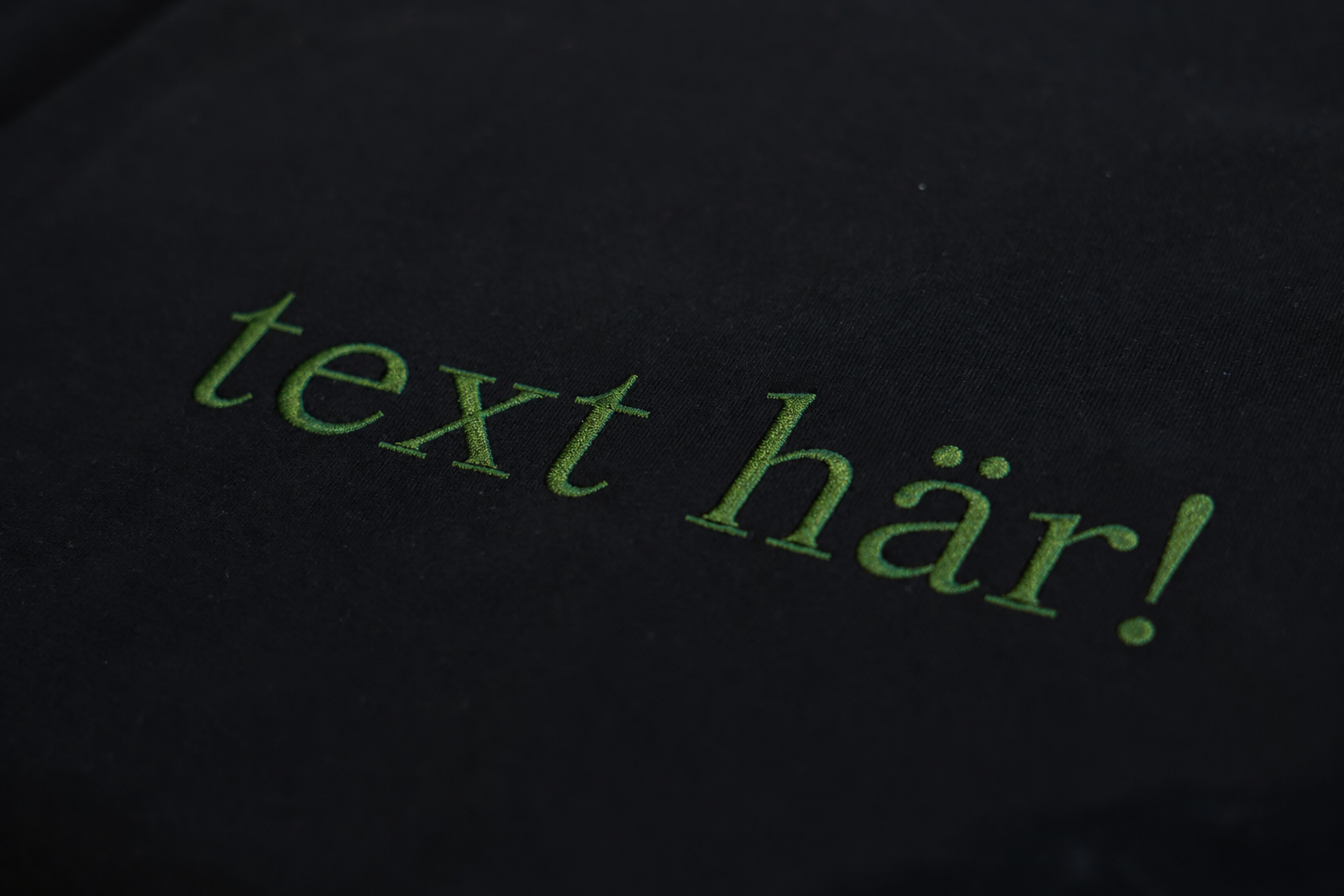 Grön broderad text på t-shirt. 